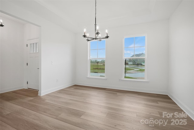 unfurnished dining area with light wood-type flooring, baseboards, and an inviting chandelier