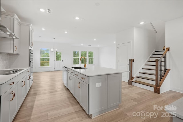 kitchen featuring light wood finished floors, visible vents, black electric stovetop, light countertops, and a sink