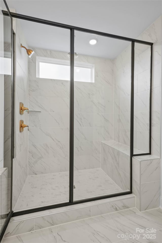 bathroom with marble finish floor, a shower stall, and a wealth of natural light