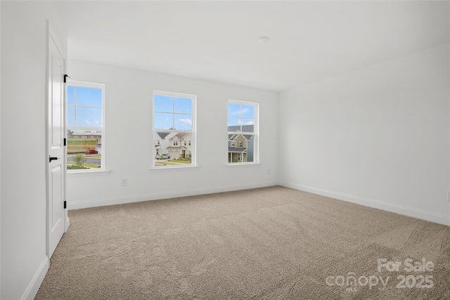 spare room featuring carpet floors and baseboards