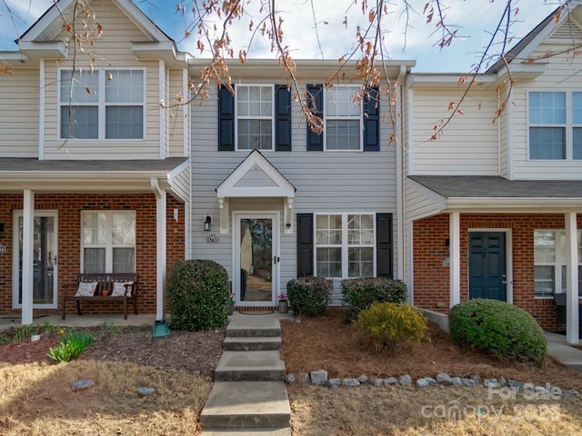 multi unit property featuring covered porch and brick siding