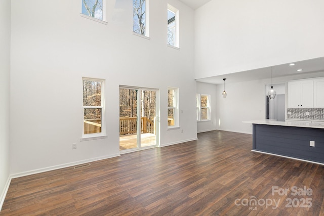 unfurnished living room featuring dark wood-style floors, baseboards, visible vents, and recessed lighting