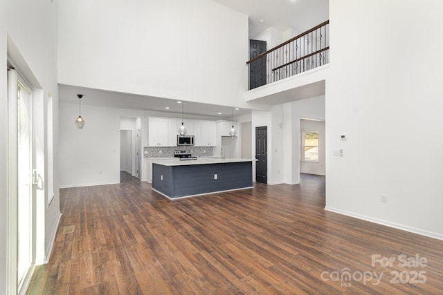 unfurnished living room featuring a high ceiling, baseboards, dark wood-style flooring, and recessed lighting