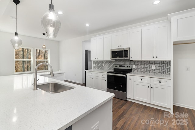 kitchen featuring white cabinets, decorative backsplash, stainless steel appliances, and a sink