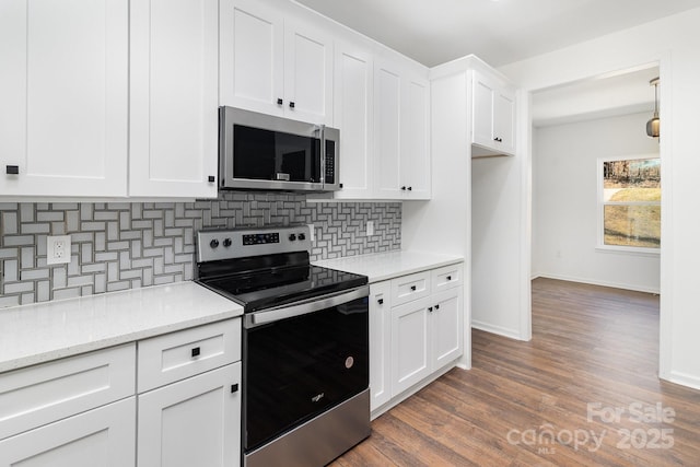 kitchen with stainless steel appliances, wood finished floors, baseboards, white cabinets, and tasteful backsplash