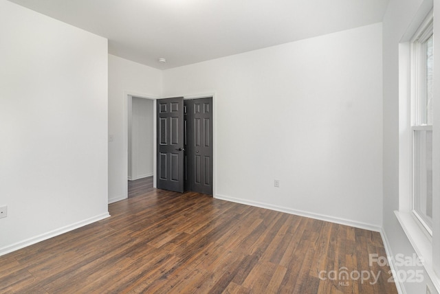 empty room featuring dark wood-style floors and baseboards