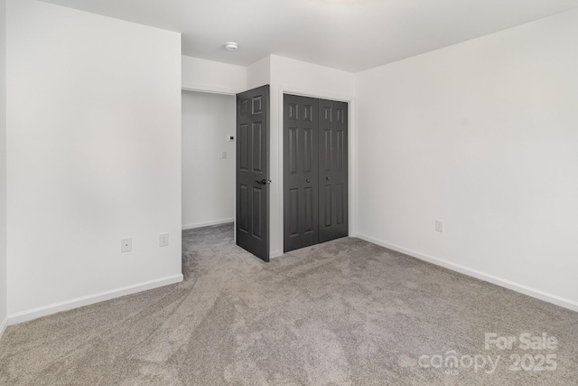 unfurnished bedroom with carpet, a closet, and baseboards