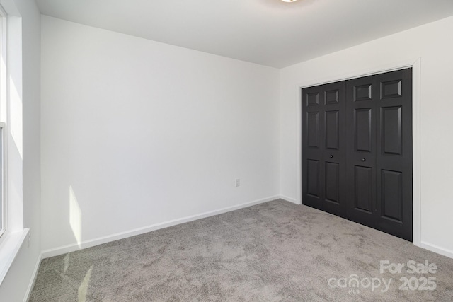 unfurnished bedroom featuring carpet floors, a closet, and baseboards