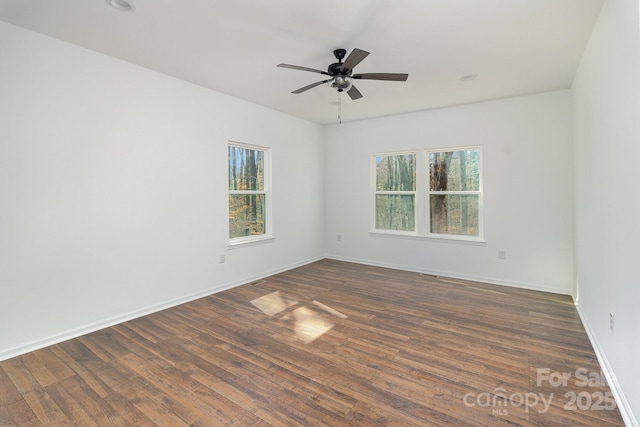 unfurnished room featuring baseboards, dark wood finished floors, and a ceiling fan