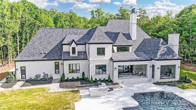 view of front of home featuring central AC, a patio area, a chimney, and stucco siding