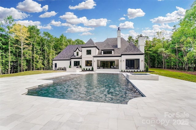 pool with a patio area, a lawn, and an in ground hot tub