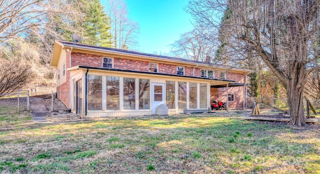 rear view of house featuring brick siding, a yard, a sunroom, a gate, and fence