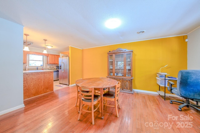 dining room featuring light wood-type flooring, baseboards, and ornamental molding