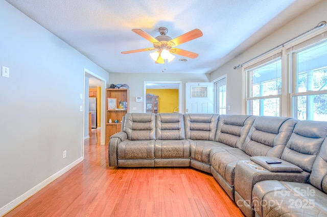 living area with baseboards, ceiling fan, and light wood-style floors