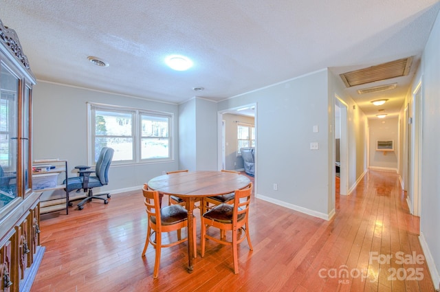 dining area with baseboards, a healthy amount of sunlight, a textured ceiling, and light wood finished floors