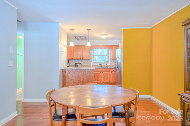 dining area featuring light wood finished floors and baseboards