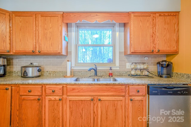 kitchen featuring dishwasher, a sink, light stone countertops, and decorative backsplash