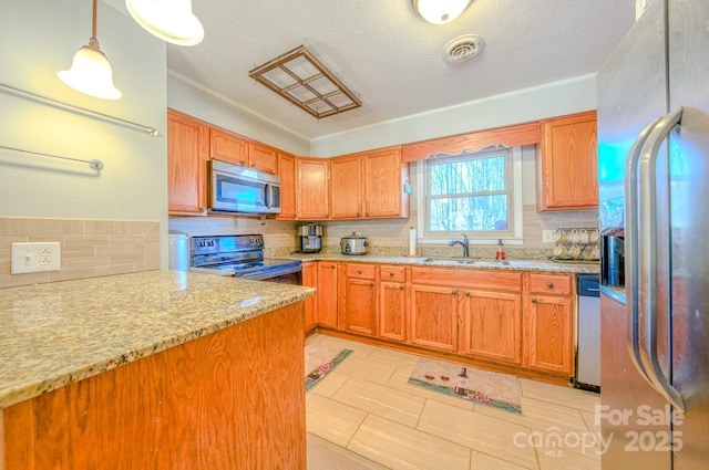 kitchen featuring light stone counters, stainless steel appliances, a sink, visible vents, and tasteful backsplash