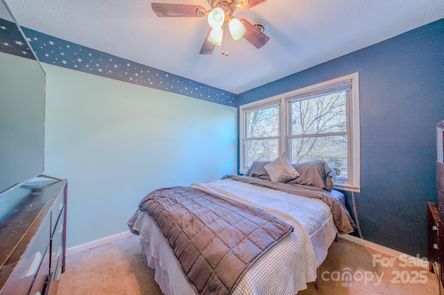 carpeted bedroom with a textured ceiling, baseboards, and a ceiling fan