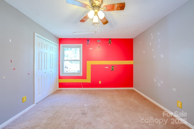 unfurnished room featuring ceiling fan, carpet floors, a textured ceiling, and baseboards