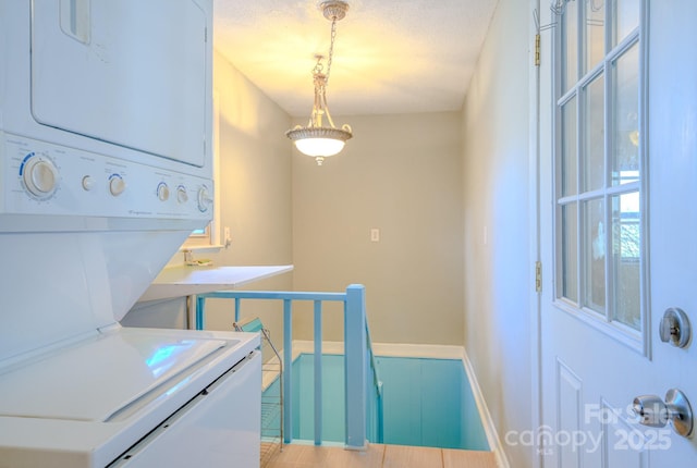 washroom with stacked washing maching and dryer, baseboards, laundry area, and a textured ceiling