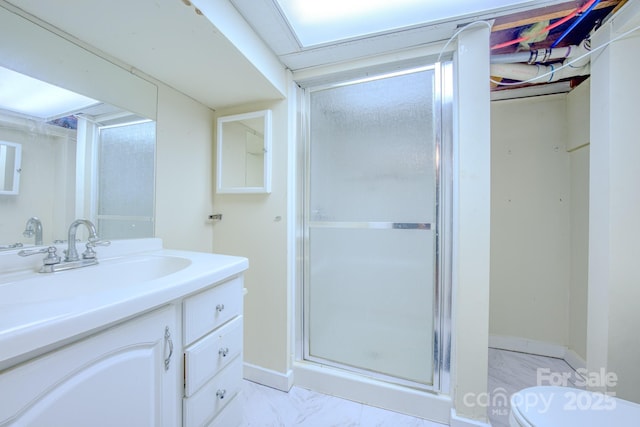 full bathroom with marble finish floor, toilet, a stall shower, vanity, and baseboards