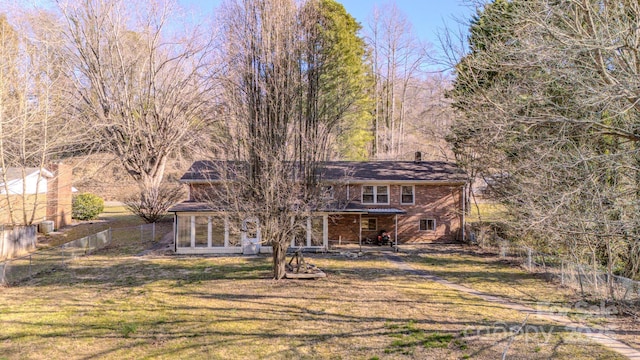 back of property with brick siding, fence, and a yard