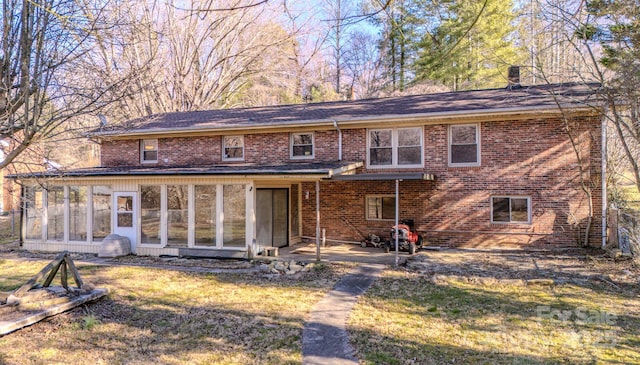 rear view of house with a sunroom, brick siding, and a yard