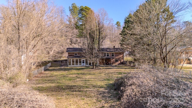 rear view of property featuring a lawn and fence