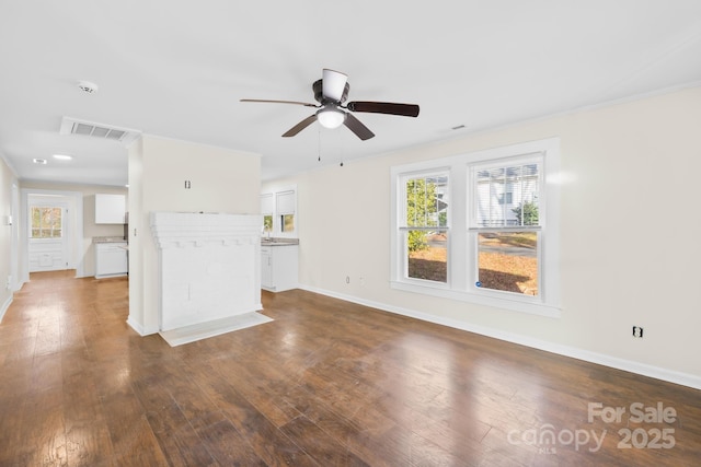 unfurnished living room featuring a healthy amount of sunlight, baseboards, visible vents, and dark wood-style flooring