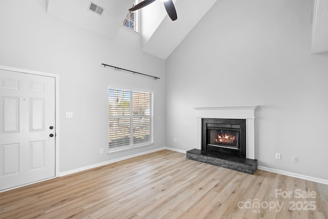 unfurnished living room featuring high vaulted ceiling, wood finished floors, visible vents, baseboards, and a lit fireplace