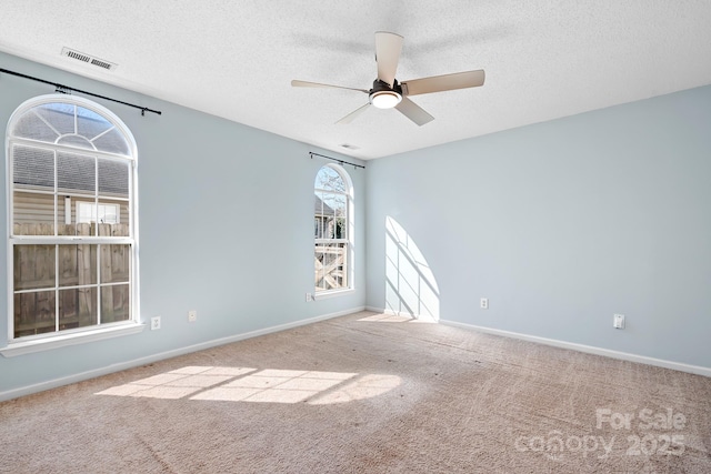 empty room featuring a ceiling fan, carpet, visible vents, and baseboards