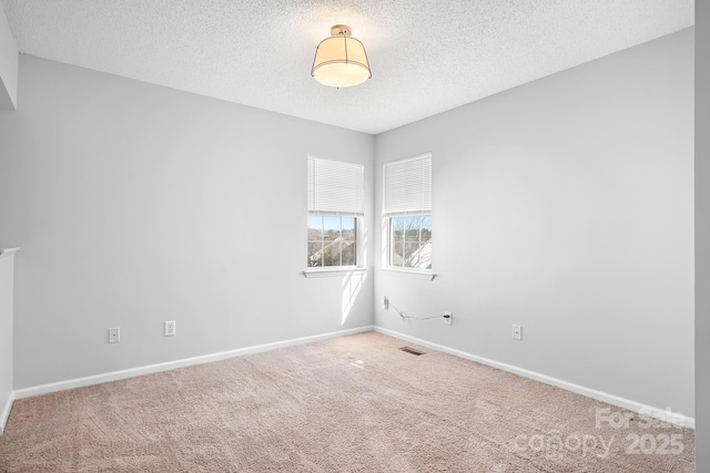 unfurnished room with carpet floors, visible vents, a textured ceiling, and baseboards