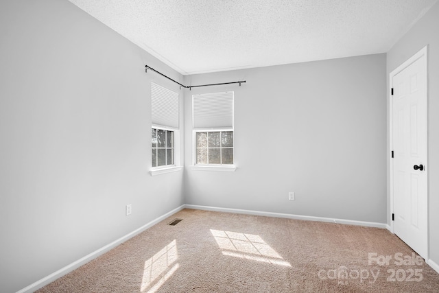 carpeted empty room with baseboards, visible vents, and a textured ceiling