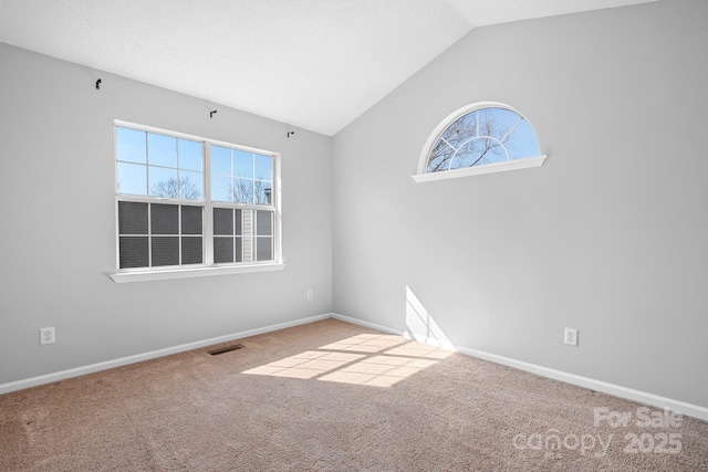 carpeted empty room featuring lofted ceiling, baseboards, and visible vents