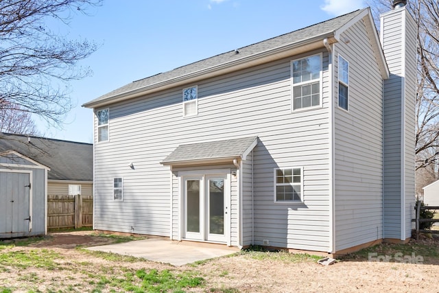 rear view of property featuring a chimney, an outbuilding, fence, a patio area, and a shed