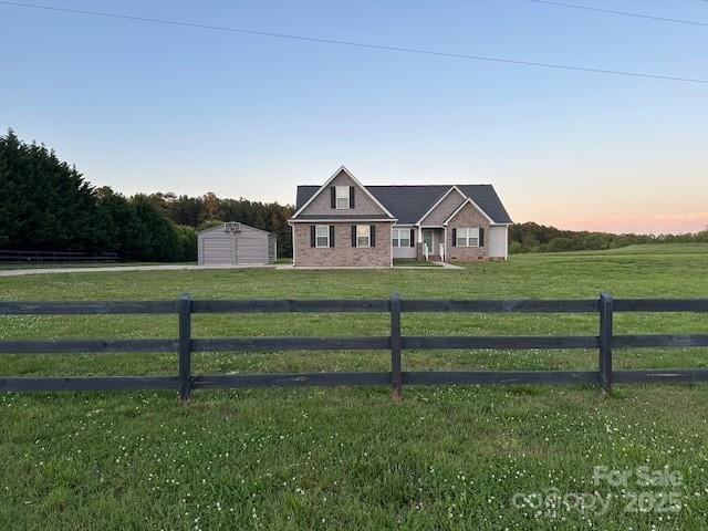 view of front of house featuring fence, a lawn, and a rural view