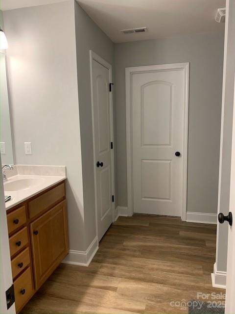 bathroom with baseboards, visible vents, wood finished floors, and vanity