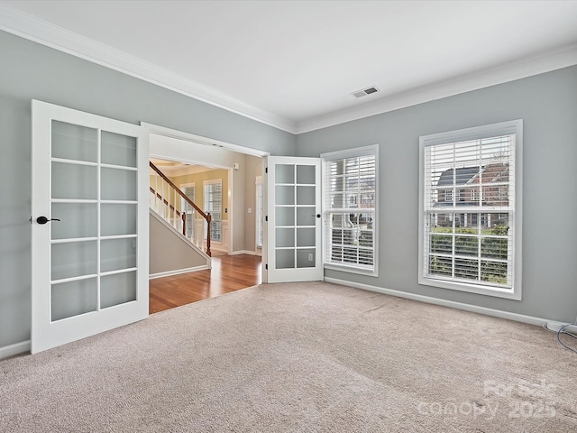 carpeted empty room with stairs, crown molding, french doors, and baseboards