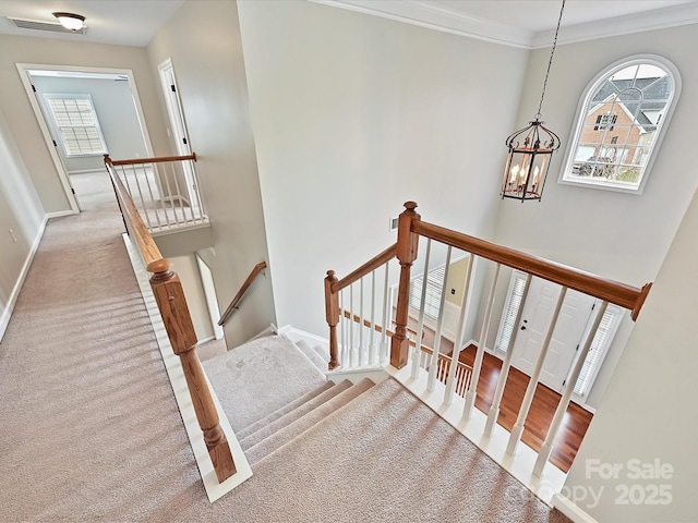 stairway featuring carpet, baseboards, visible vents, crown molding, and a chandelier