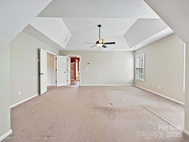 carpeted spare room featuring baseboards, a raised ceiling, a ceiling fan, and vaulted ceiling