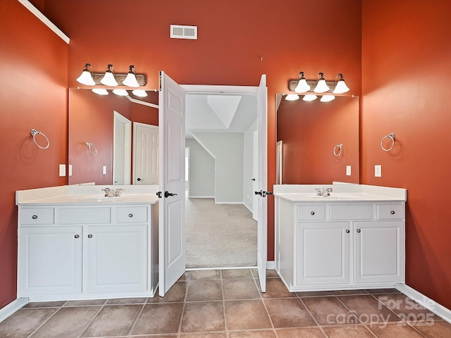 full bath featuring visible vents, two vanities, and a sink