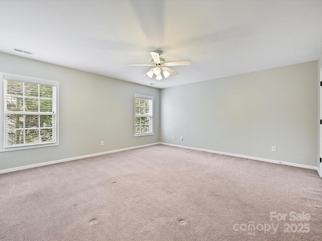 carpeted empty room with visible vents, baseboards, and a ceiling fan