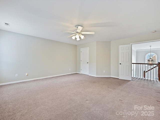 spare room featuring carpet, ceiling fan with notable chandelier, visible vents, and baseboards