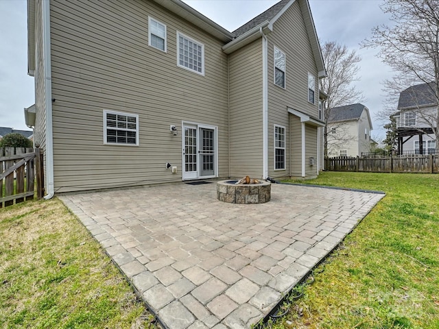 rear view of property featuring a patio, a lawn, a fenced backyard, and a fire pit