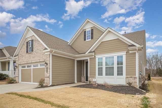 craftsman-style home featuring a garage, a shingled roof, concrete driveway, and brick siding