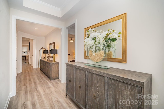 hallway with ornamental molding, light wood-style flooring, and baseboards