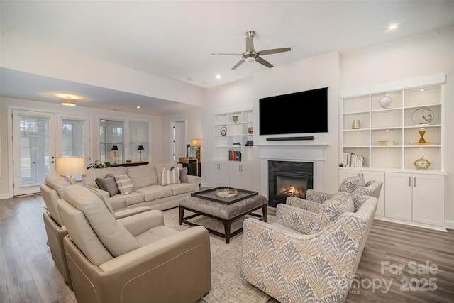 living area featuring a ceiling fan, a glass covered fireplace, recessed lighting, and wood finished floors