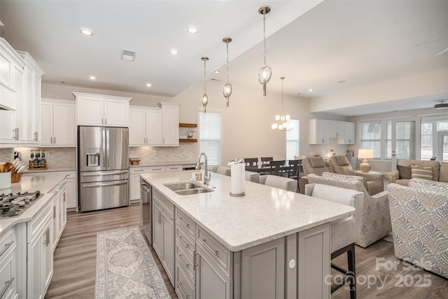 kitchen with an island with sink, open floor plan, a kitchen breakfast bar, stainless steel appliances, and a sink