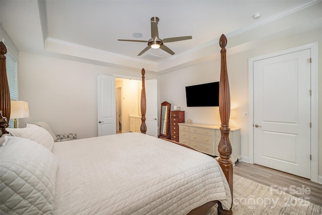 bedroom featuring ornamental molding, a tray ceiling, light wood-style flooring, and a ceiling fan